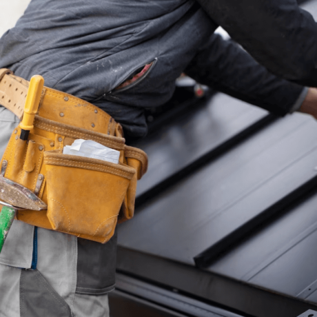 roofing professional using a tape measure to measure a roof